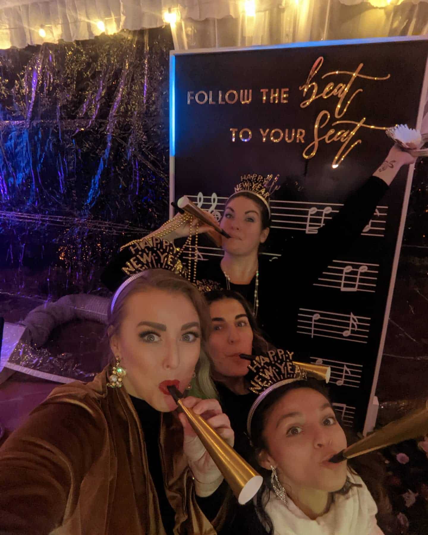 Group of women celebrating New Year's at Type A Soiree with party hats and noise makers.