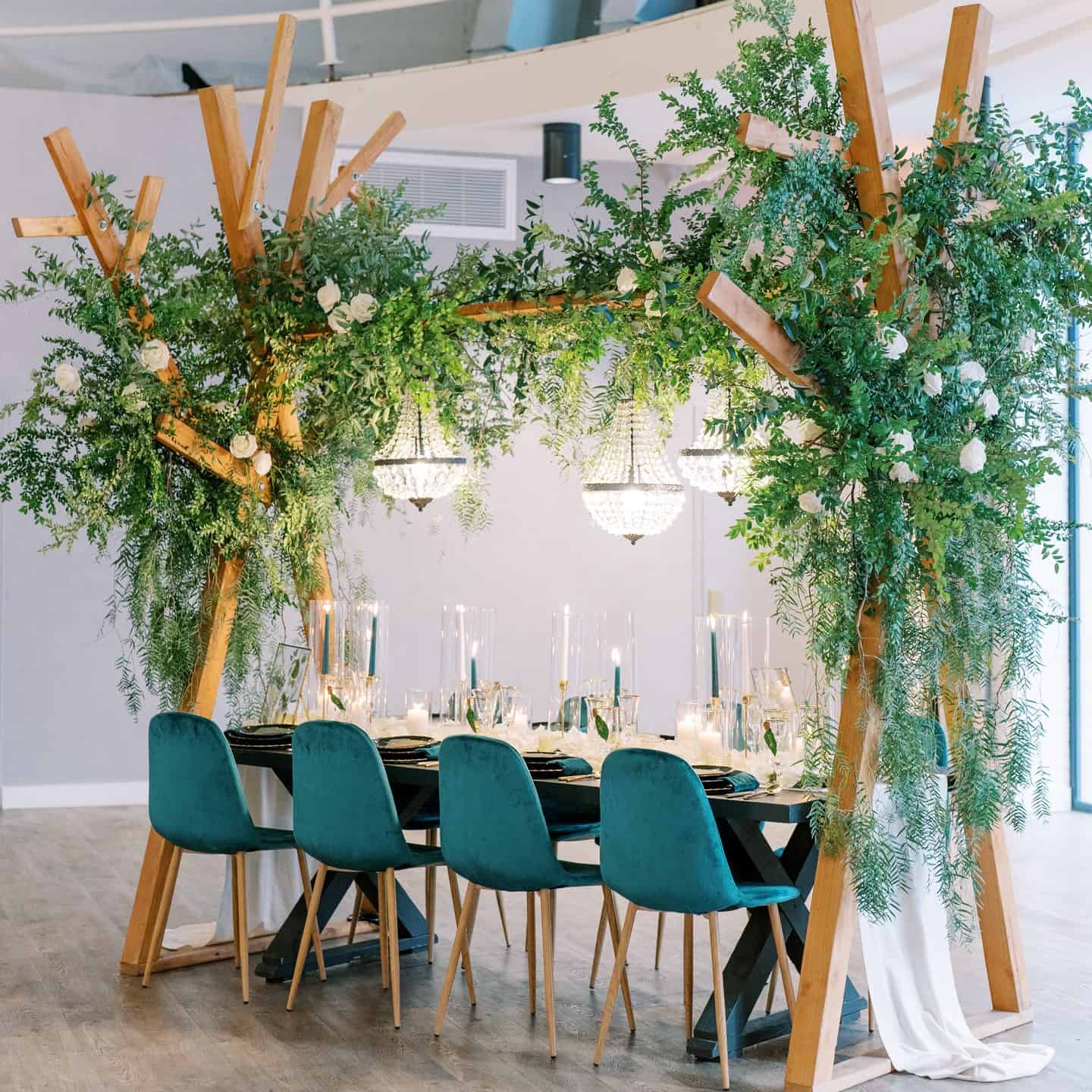 Wedding reception table decorated with greenery and elegant lighting.