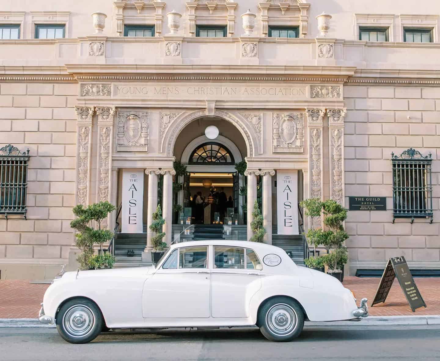 Elegant event entrance with vintage car at Young Men's Christian Association building.