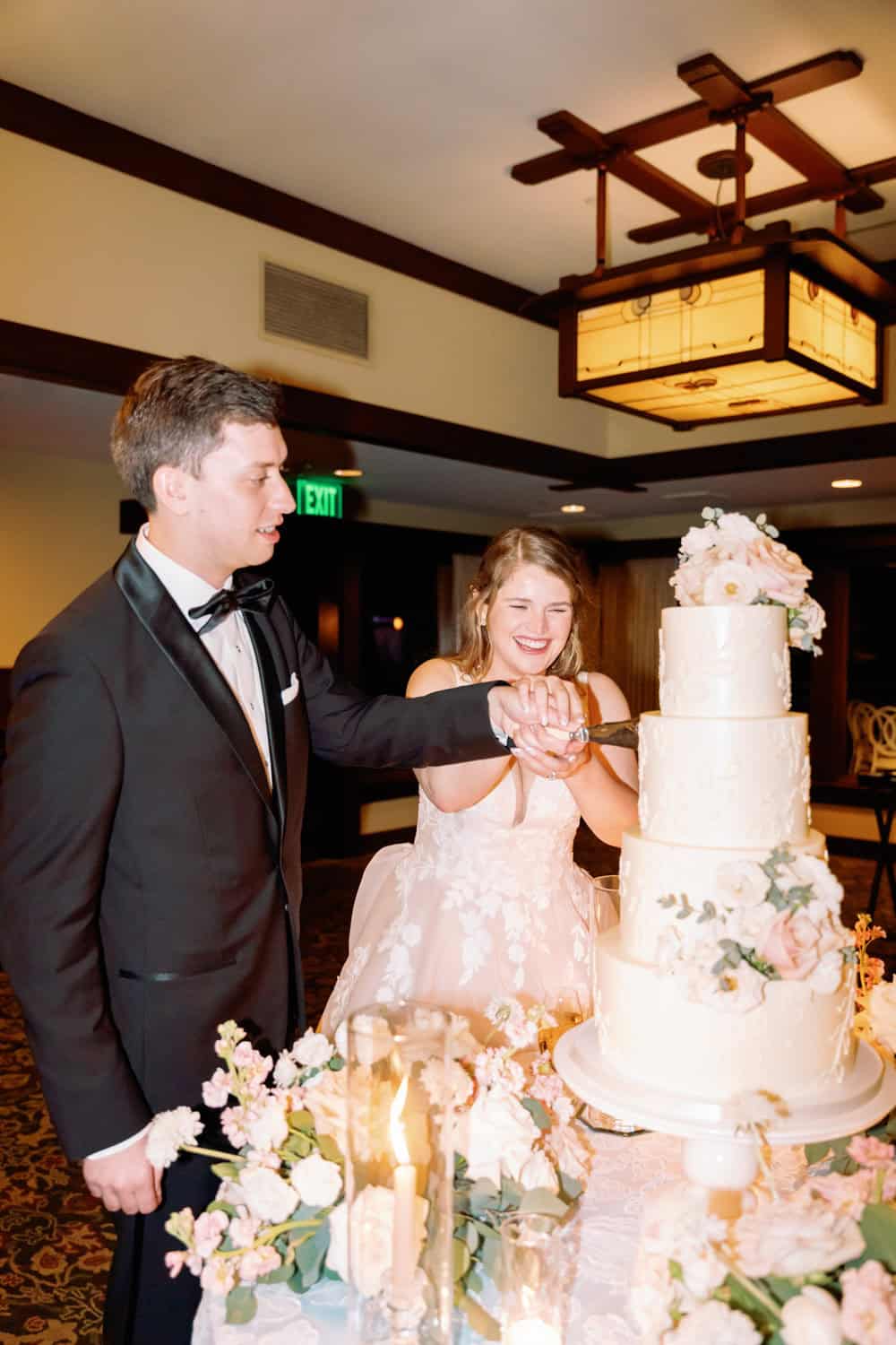Elegant couple cutting wedding cake at formal celebration.
