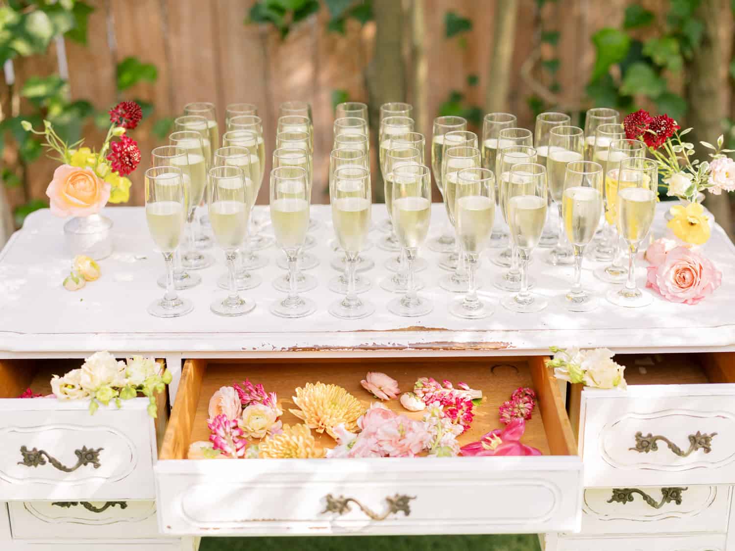 Champagne glasses arranged on a table for a stylish event, decorated with flowers and floral accents.