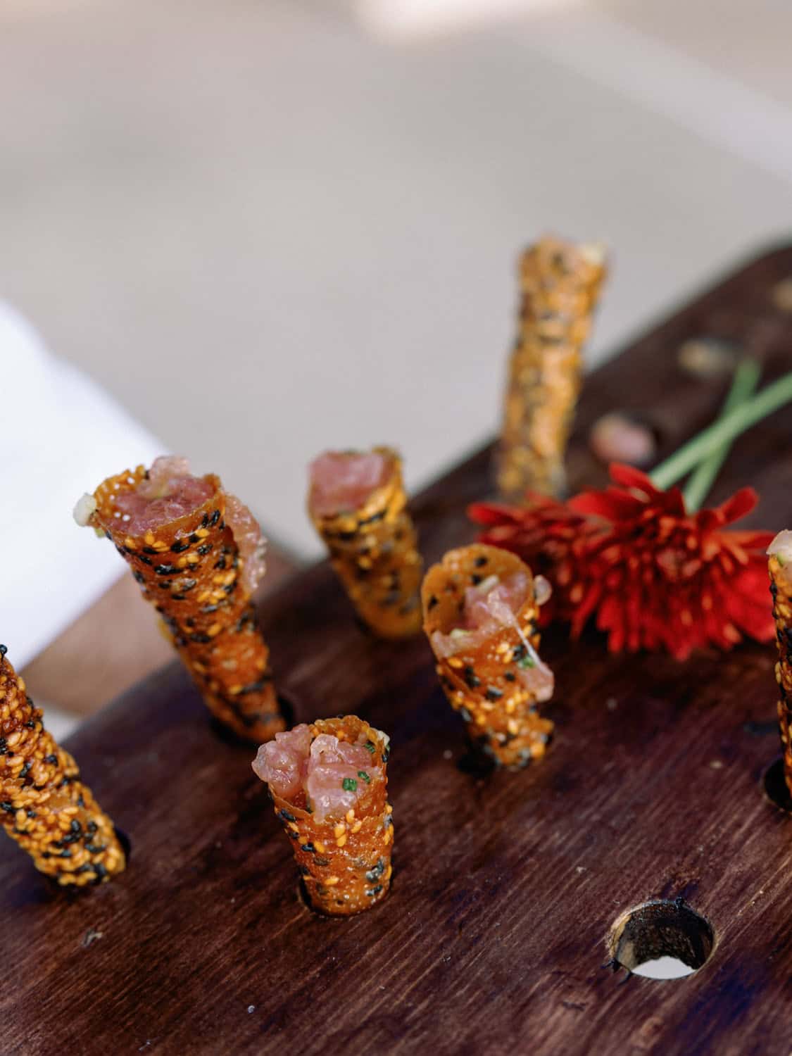 Delicious sesame-crusted appetizers with savory fillings, served on a wooden platter for a stylish e.