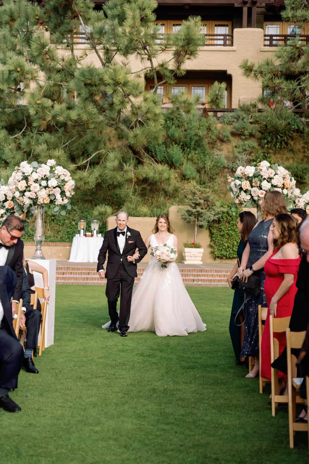 Outdoor wedding ceremony with bride and groom walking down the aisle.