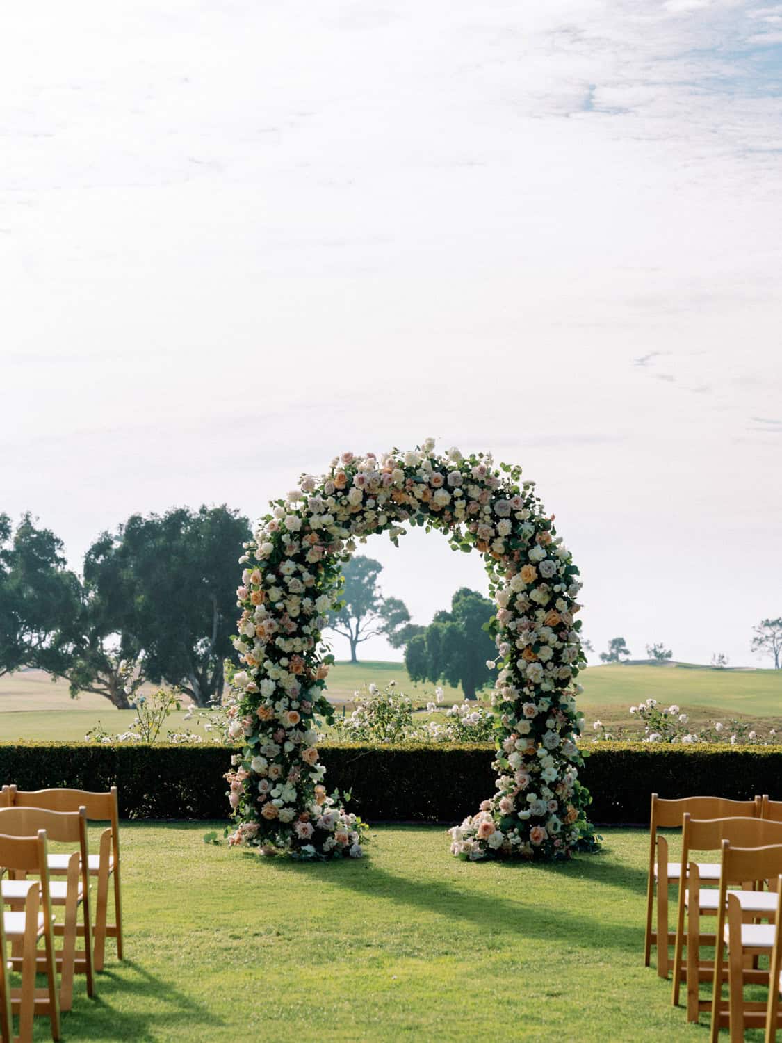 Wedding arch with floral arrangements for outdoor ceremony.