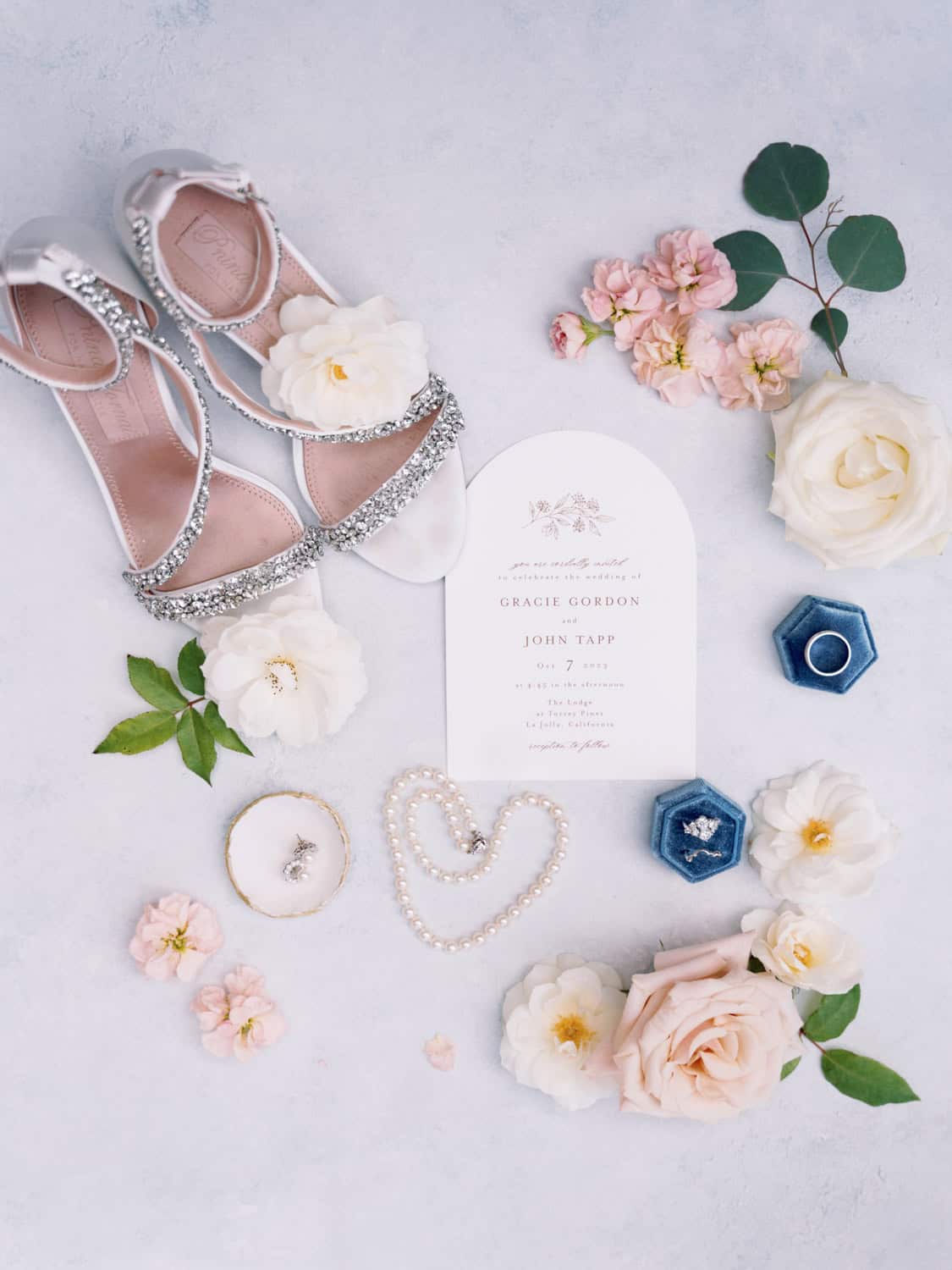Elegant wedding shoes with rhinestones and floral invitation for a stylish soirée.