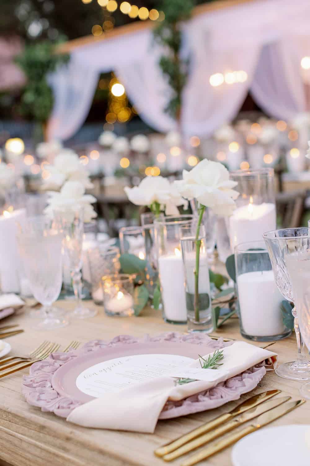 Elegant wedding reception table with white flowers, candles, and sophisticated decor.