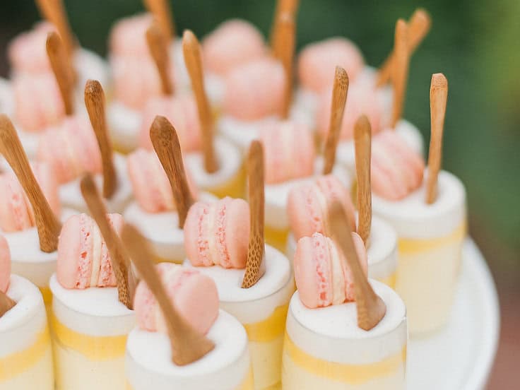 Assorted mini desserts with pink macarons and wooden sticks at Type A Soiree.
