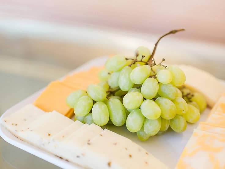 Fresh green grapes with cheese and crackers at a stylish event.