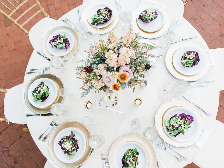 Elegant floral table setting with purple and white accents for a stylish soiree. Perfect for upscale.