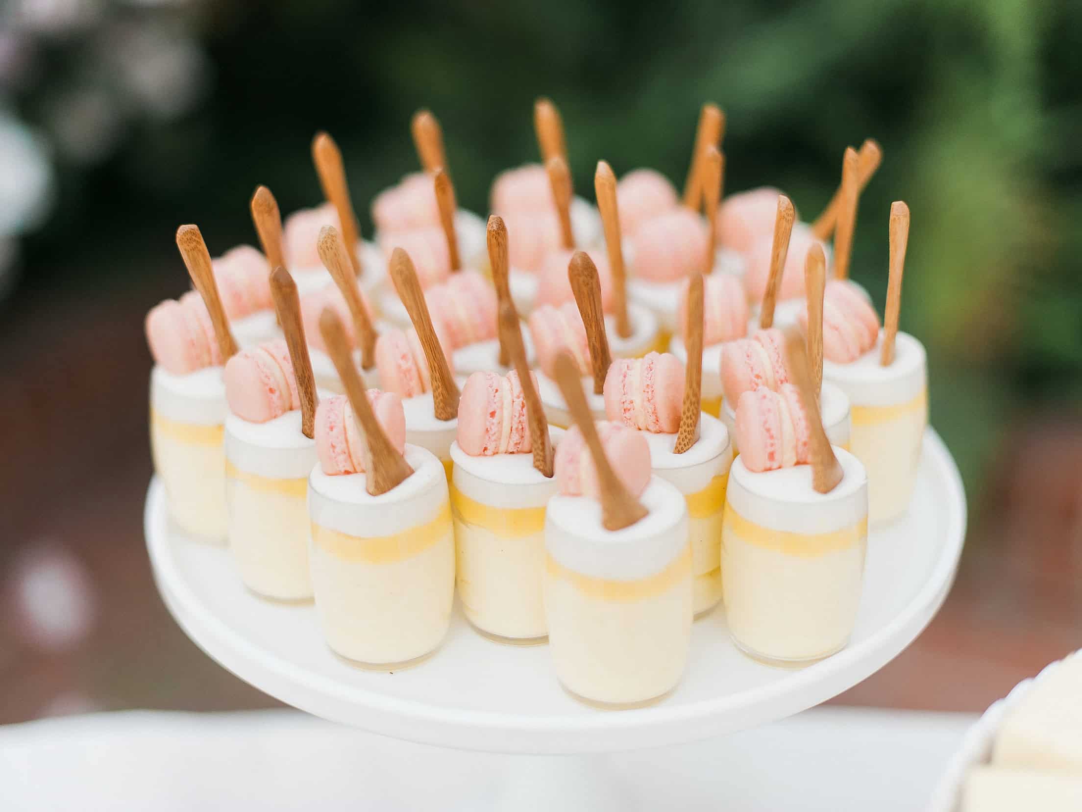 Mini cheesecake bites with pink macarons and wafer sticks for elegant dessert table.