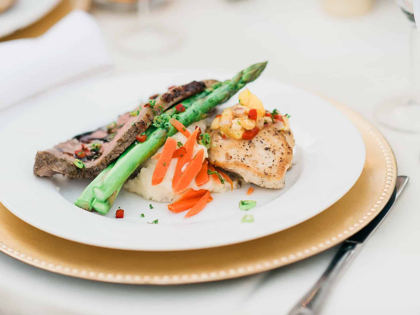 Delicious grilled chicken served with asparagus, carrots, and mashed potatoes on a white plate.
